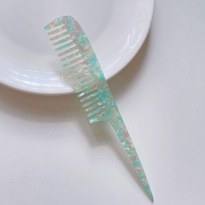 Detailed view of pale green marble texture acetate tail comb with wide teeth on white plate