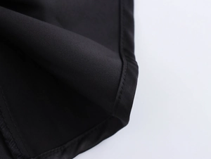 Close-up of black satin dress fabric showing fine texture and quality stitching details