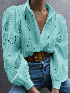 Detail of light blue embroidered blouse featuring puff sleeves and intricate hollow cut-outs