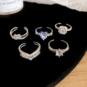 Detailed view of five zircon silver rings with heart and geometric designs on black velvet