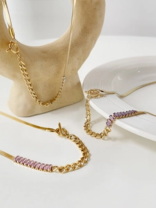 Detail of gold snake chain with colorful baguette zircon stones and toggle clasp design