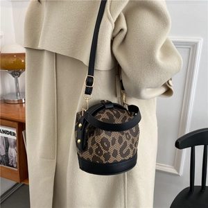 Chic leopard print bucket bag with black leather trim and adjustable strap on a model