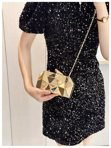 Close-up of golden geometric evening clutch with metallic mirror finish and chain
