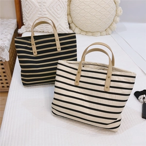 Detail of striped canvas tote bags with leather handles and metallic rivet reinforcement