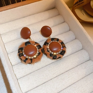Macro detail of leopard print earrings with rhinestones and plush texture