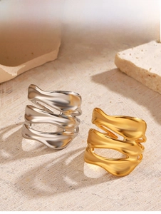 Detail shot of gold and silver irregular wave rings on a rustic stone background