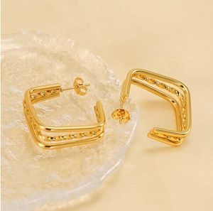 Detail view of square triple-layered gold earrings with twisted rope texture and metal luster