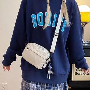Close-up of off-white crossbody bag with front zipper pocket and adjustable strap