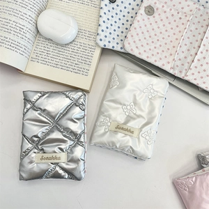 Detail of silver metallic quilted tablet sleeve with bow embroidery on background