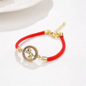 Détail du pendentif MAMA doré avec pierres de zircon colorées sur cordon rouge tressé