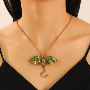 Detail view of a vintage gold-tone dragon pendant with green enamel and sparkling crystals
