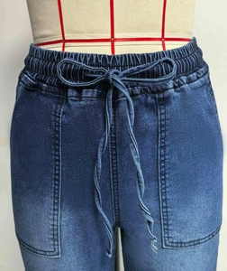 Detail van de elastische taille met trekkoord en grote opgestikte zakken op de jeans