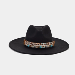 Detail of ethnic woven band with shell and star charms on a black wide brim fedora hat