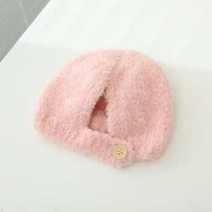 Detail of soft pink plush baby hat with fluffy faux fur texture and beige button accent