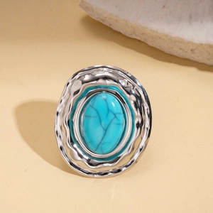 Macro shot of oval turquoise stone ring with wavy silver hammered metal finish detail