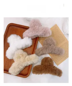 Detail of five plush faux fur claw clips in various neutral colors on a wooden tray