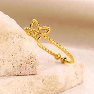Adjustable gold butterfly ring with twisted band on natural stone background