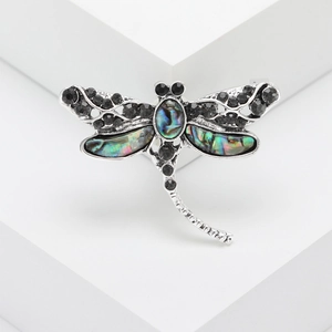 Vintage dragonfly brooch with abalone shell and black rhinestones on a white pedestal