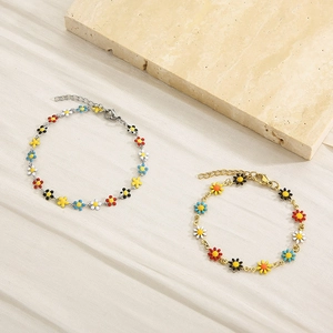 Detail of colorful enamel daisy charms on gold and silver stainless steel bracelets