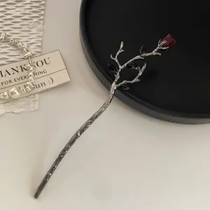 Close-up of retro silver tassel hair pin with dark red rose bud and black crystals