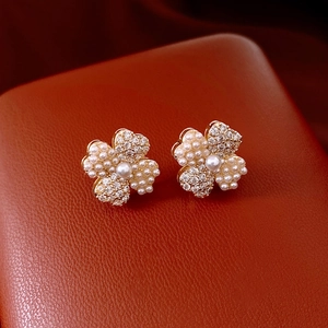 Macro detail of 14K gold plated flower earrings with pearls and crystals on leather