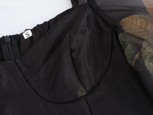 Gros plan sur le corsage noir plissé et les manches en organza à motifs de feuilles