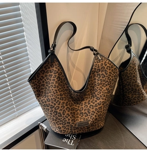 Detailed close-up of leopard print tote bag with leather straps on a reflective surface