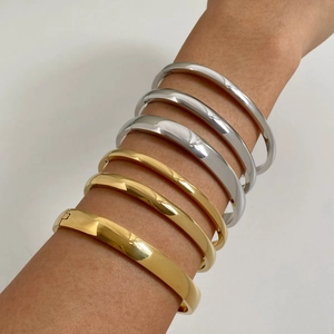Minimalist gold and silver stainless steel hinged bangles stacked on a woman's arm