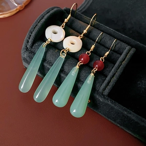 Detail of Chinese style drop earrings with green jade resin and shell in a jewelry box