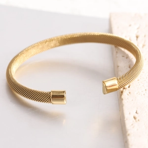 Close-up of golden stainless steel 7mm mesh cuff bracelet with smooth end caps