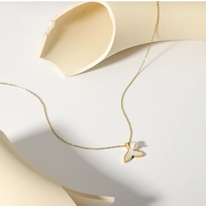 Close-up of golden mermaid tail pendant featuring white pearl and natural mother of pearl