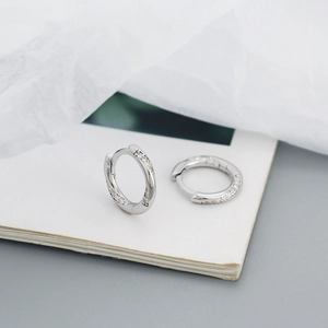 Macro shot of silver S925 huggie hoop earrings with micro-paved crystal zircons