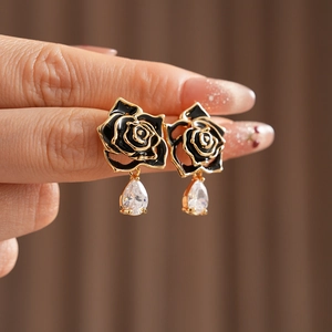 Gros plan détaillé de boucles d'oreilles fleurs en émail noir vintage et zircon doré