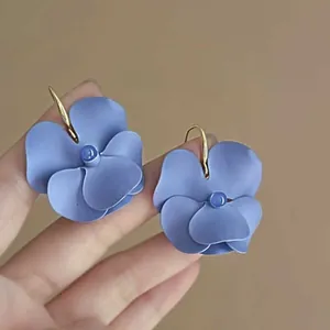 Detail view of blue pansy flower drop earrings with matte finish and gold-tone hooks
