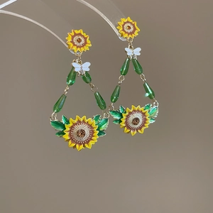 Detail of sunflower drop earrings with white butterfly and green bead accents