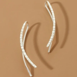 Detailed macro view of silver minimalist hook earrings with unique hammered metal texture