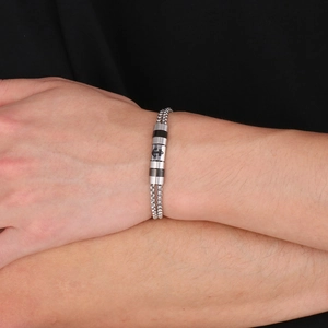 Dettaglio di un bracciale a doppia catena industriale con ancora in nero e argento