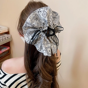 Detail of a large black and white paisley bow hair claw clip with elegant pearl accents