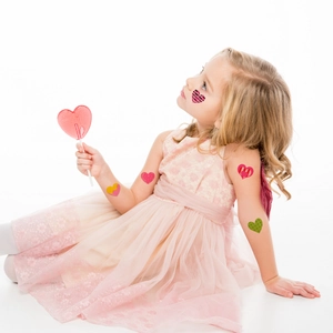 Kids colorful heart temporary tattoo stickers on girl cheek and arm for festivals