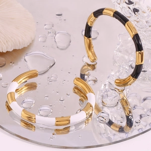 Close-up of bamboo-style gold-plated bangles with black and white enamel details