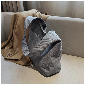 Nahaufnahme einer grauen Cord-Einkaufstasche auf einem beigen Sofa mit einem Blazer