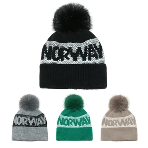 Detail view of four Norway jacquard beanies with large faux fur pom poms and knit texture