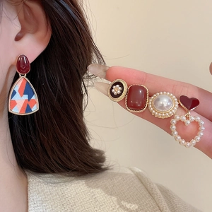 Close-up of vintage resin pearl earrings set with red hearts on a model's ear