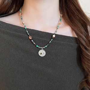 Détail d'un collier bohème perlé avec pendentif lune et étoile sur le cou d'un mannequin