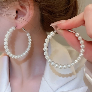 Close-up of elegant silver hoop earrings featuring a sequence of white round pearls