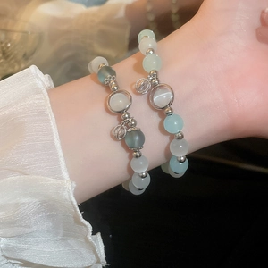 Detail of beaded cat-eye stone bracelets featuring a silver lucky pouch charm for women