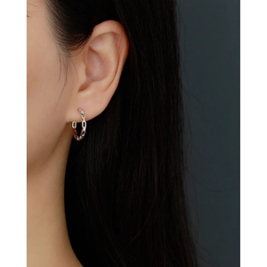 Close-up of geometric silver chain link hoop earrings with diamonds worn by a model