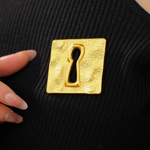 Macro shot of vintage gold square brooch with keyhole design on black fabric