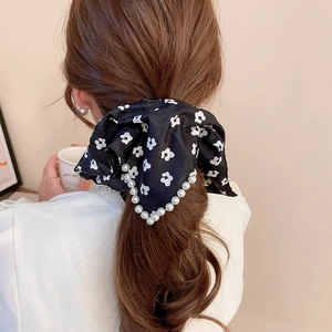Detail of floral satin scrunchie with pearl trim on an elegant low ponytail hairstyle