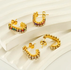 Macro detail of gold U-shaped earrings with colorful and clear cubic zirconia inlays